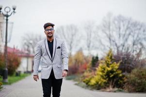 elegante uomo indiano con bindi sulla fronte e occhiali, indossa un abito posato all'aperto. foto