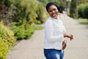 ragazza musulmana africana in hijab nero, felpa bianca e jeans in posa all'aperto. foto