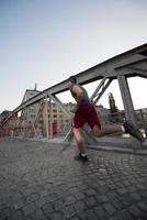 uomo che fa jogging attraverso il ponte al mattino soleggiato foto