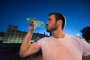 uomo che beve acqua dopo la sessione di corsa foto