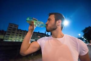 uomo che beve acqua dopo la sessione di corsa foto