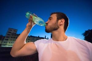 uomo che beve acqua dopo la sessione di corsa foto