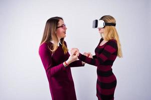 due ragazze in abiti viola che provano occhiali per realtà virtuale in studio. foto