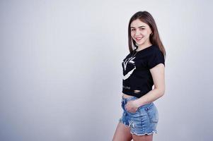 ritratto di una ragazza attraente in maglietta nera che dice lol e pantaloncini di jeans in posa in studio. foto