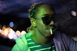 uomo afroamericano che fuma sigaretta di notte foto