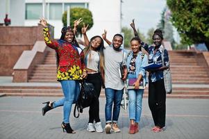 gruppo di cinque studenti universitari africani che trascorrono del tempo insieme nel campus nel cortile dell'università. amici afro neri che studiano. tema dell'educazione. foto