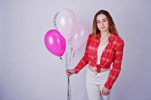 giovane ragazza in camicia rossa a quadri e pantaloni bianchi con palloncini su sfondo bianco in studio. foto