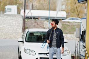 uomo del sud asiatico o maschio indiano che lava il suo trasporto bianco sull'autolavaggio. foto