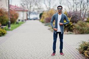 l'uomo indiano alla moda con gli occhiali da sole indossa una posa casual all'aperto. foto