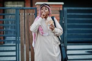 uomo d'affari arabo mediorientale posato su strada contro un edificio moderno con borsetta nera e denaro in euro. foto