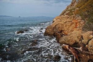 l'onda del mare si rompe sul paesaggio delle rocce della spiaggia. le onde del mare si infrangono e schizzano sulle rocce a Bodrum, in Turchia. foto