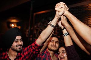 gruppo di amici indiani che si divertono e riposano al night club e danno il cinque insieme. foto
