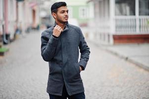 elegante uomo indù indiano in cappotto grigio posato sulla strada. foto