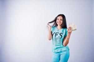 ritratto di una ragazza attraente in maglietta e pantaloni blu o turchese in posa con molti soldi in mano. foto