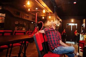 l'uomo asiatico fuma narghilè e riposa al lounge bar. foto
