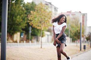 modello slim afroamericano dalla pelle scura posato in pantaloncini di pelle neri e t-shirt bianca. foto