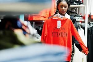 donne americane in tute da ginnastica che fanno shopping al centro commerciale di abbigliamento sportivo contro scaffali con felpa. tema del negozio di sport. foto