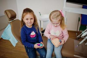 due piccole bambine carine alla poltrona del dentista. bambini dentali. foto
