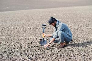 agronomo agricoltore del sud asiatico con pala che ispeziona il suolo nero. concetto di produzione agricola. foto