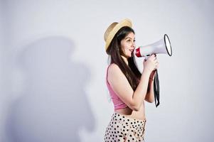 ritratto di una splendida ragazza in costume da bagno e cappello parla nel megafono in studio. foto