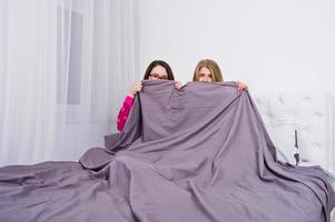 due amiche in pigiama che si divertono sul letto in camera. foto