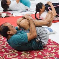 nuova delhi, india, 19 giugno 2022 -sessione di esercizi di yoga di gruppo per persone di diverse età nel tempio di balaji, vivek vihar, giornata internazionale di yoga, grande gruppo di adulti che frequentano lezioni di yoga nel tempio foto