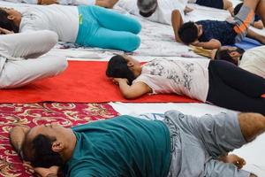 nuova delhi, india, 19 giugno 2022 -sessione di esercizi di yoga di gruppo per persone di diverse età nel tempio di balaji, vivek vihar, giornata internazionale di yoga, grande gruppo di adulti che frequentano lezioni di yoga nel tempio foto