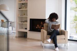 donna di colore a casa che legge il libro foto