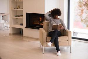 donna di colore a casa che legge il libro foto