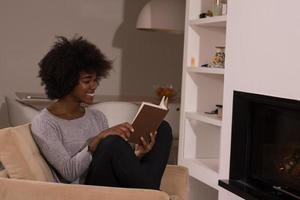 donna di colore a casa che legge il libro foto