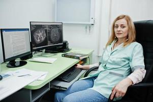 tema medico. medico nell'ufficio di risonanza magnetica del centro diagnostico in ospedale, seduto vicino a monitor di computer. foto