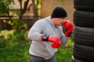 uomo pugile arabo in cappello che si allena per una dura lotta in palestra all'aperto. foto