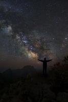 un uomo è in piedi accanto alla galassia della Via Lattea che punta su una stella luminosa, fotografia a lunga esposizione, con grana foto