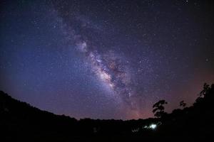 galassia della via lattea e silhouette di albero con nuvola. fotografia a lunga esposizione. con grano foto