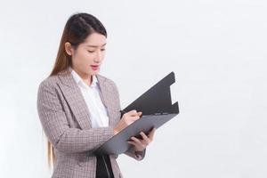 la donna d'affari asiatica dai capelli lunghi tiene in mano gli appunti mentre lavora a casa. foto