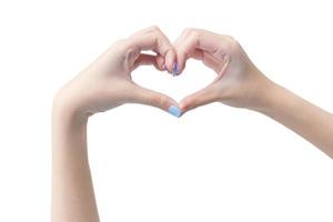 la bella mano femminile mostra il simbolo del cuore come segno d'amore su uno sfondo bianco nel concetto di manicure. foto