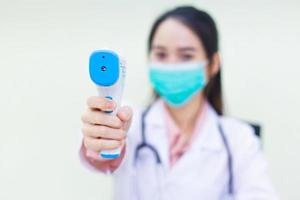 il medico asiatico della donna mostra un termometro a infrarossi sulla fronte. foto