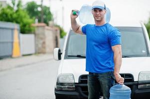 fattorino davanti al furgone che consegna bottiglie d'acqua. foto