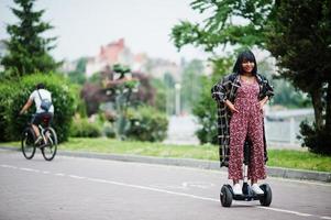 bella donna afroamericana utilizzando segway o hoverboard. ragazza nera su scooter elettrico autobilanciante a doppia ruota. foto