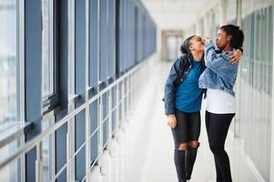 due amiche africane in giacca di jeans prendono il naso insieme al coperto. foto