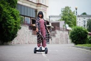 bella donna afroamericana utilizzando segway o hoverboard. ragazza nera su scooter elettrico autobilanciante a doppia ruota. foto