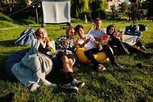 giovane gruppo multietnico di persone che guardano film al poof nel cinema all'aperto. foto