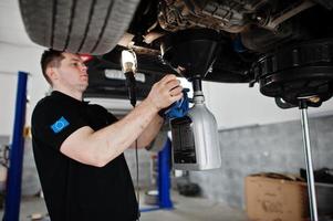 tema riparazione e manutenzione auto. meccanico in uniforme che lavora in servizio auto. foto