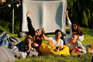 giovane gruppo multietnico di persone che guardano film al poof nel cinema all'aperto. foto