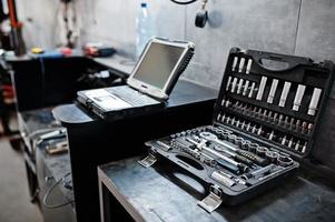laptop e strumenti in manutenzione presso la stazione di servizio del garage. foto