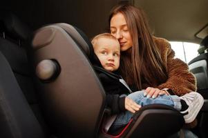 giovane madre e bambino in auto. seggiolino per bambini sulla sedia. concetto di guida di sicurezza. foto