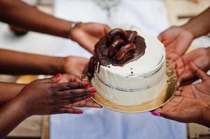 gruppo di ragazze afroamericane che celebrano la festa di compleanno all'aperto. mani nere con torta. foto