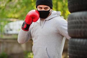 ritratto sport pugile arabo uomo in maschera medica nera boxe all'aperto durante la quarantena del coronavirus. foto