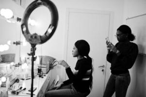 donna afroamericana che applica il trucco dal truccatore al salone di bellezza. foto