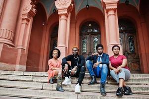 quattro amici africani hanno posato all'aperto contro la vecchia architettura. due ragazze nere con ragazzi. foto